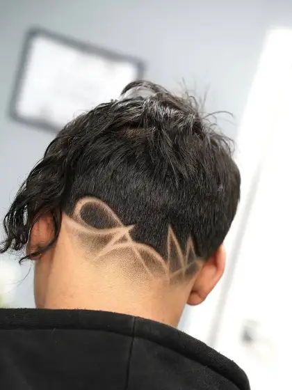 A freehand design shaved into the nape under a long textured top, cut by Leandro Herrera