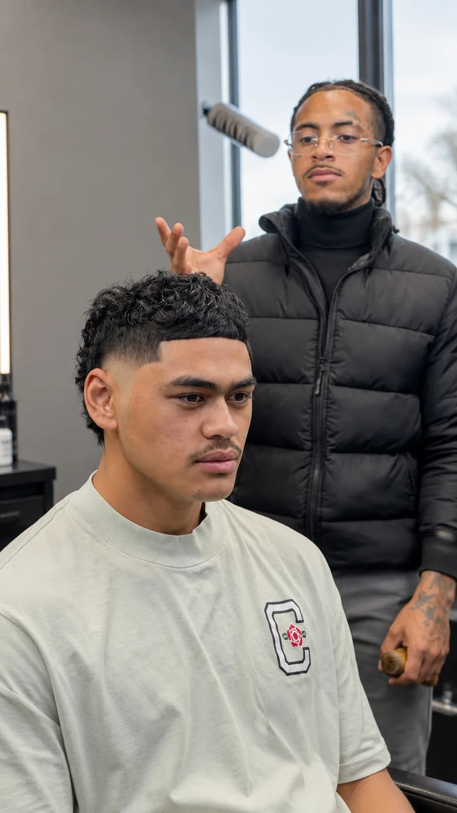 A client in the chair with Leandro talking the cut through behind him.