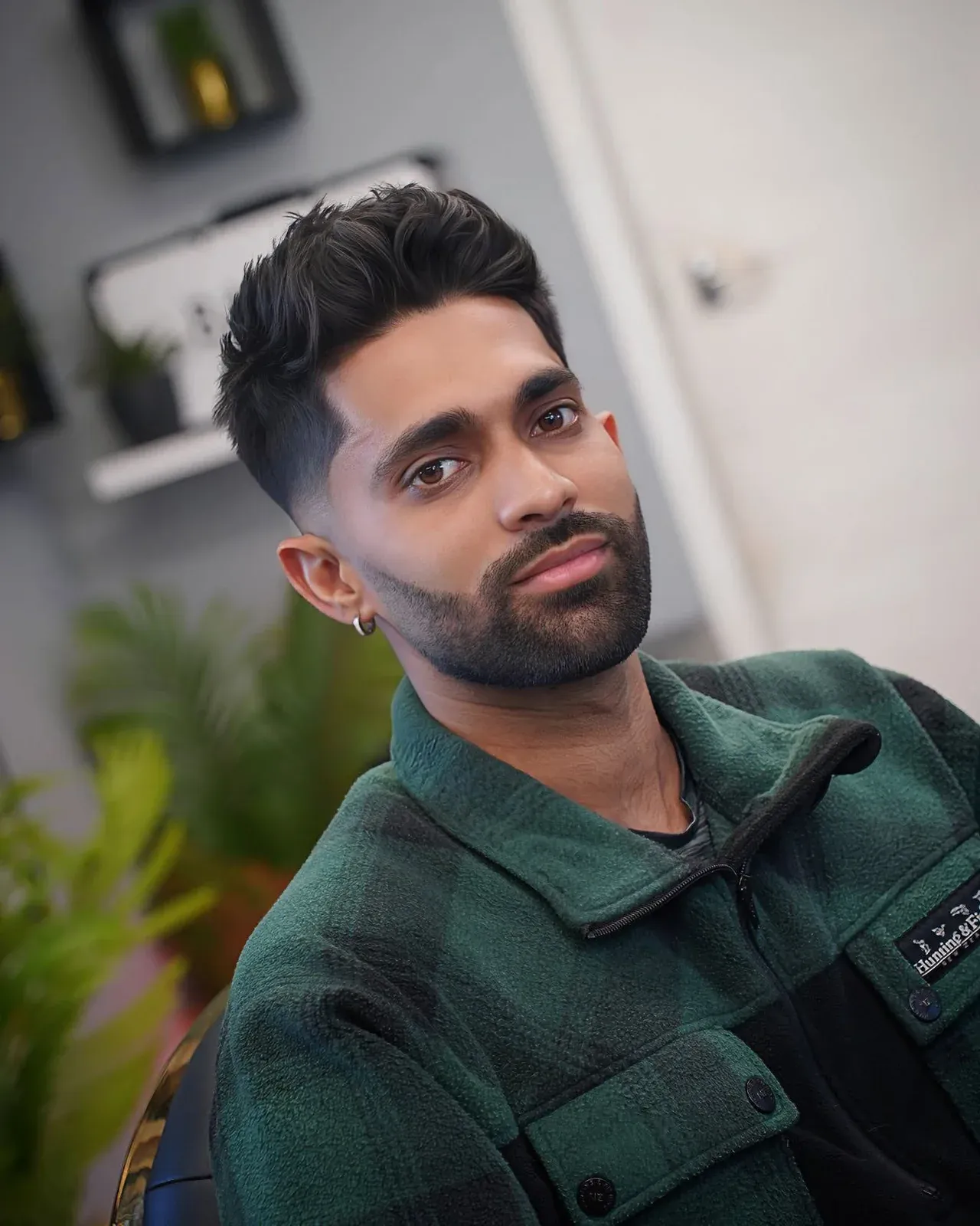 A curly top with a mid fade and a full beard, cut by Leandro Herrera