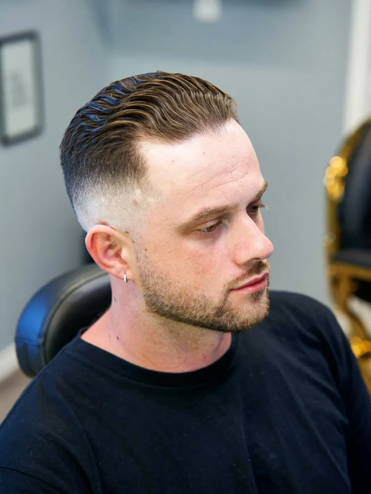 A slicked side part over a skin fade, in profile, cut by Leandro Herrera