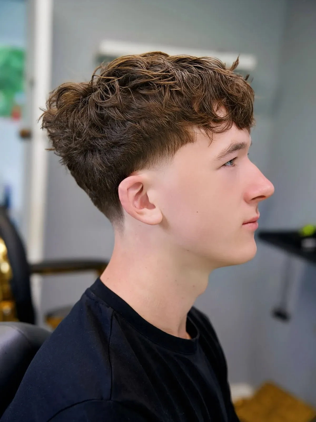 A curly top with a taper, in profile, cut by Leandro Herrera