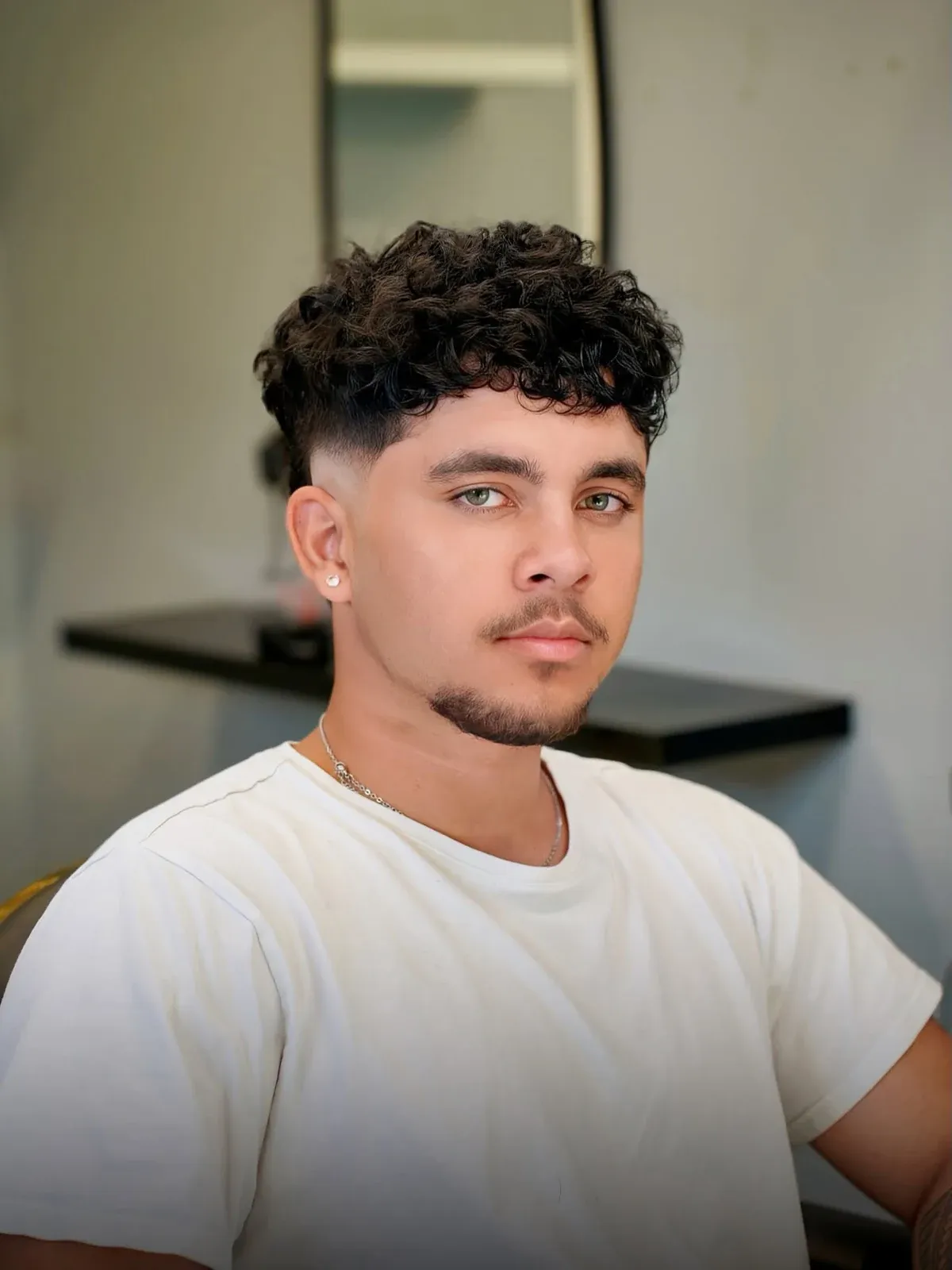 A curly top with a mid fade, cut by Leandro Herrera