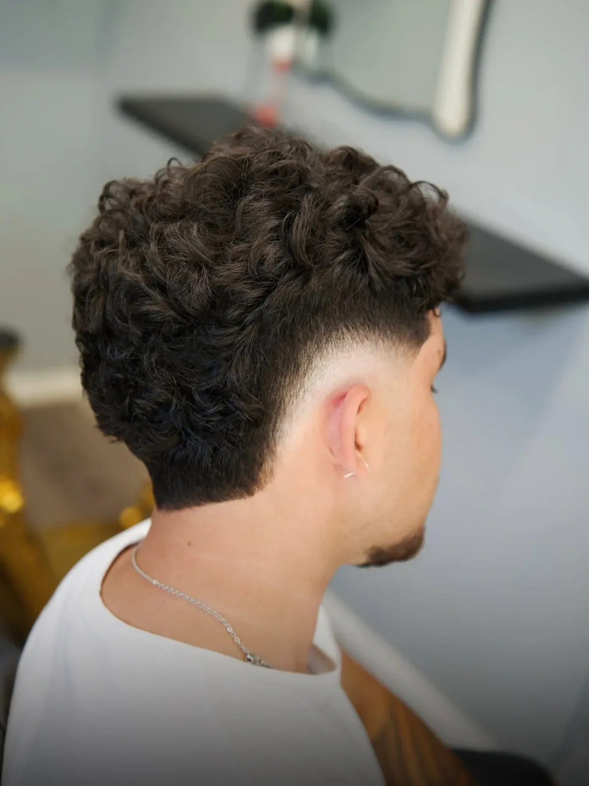 A curly top over a skin fade, from behind, cut by Leandro Herrera