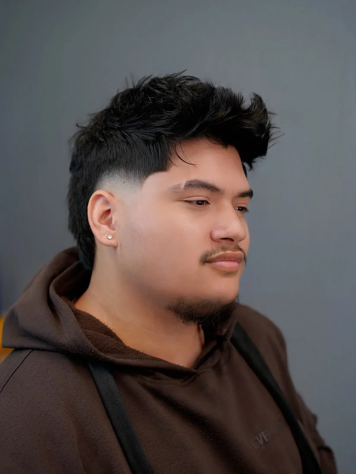 A textured quiff swept up over a low fade, cut by Leandro Herrera